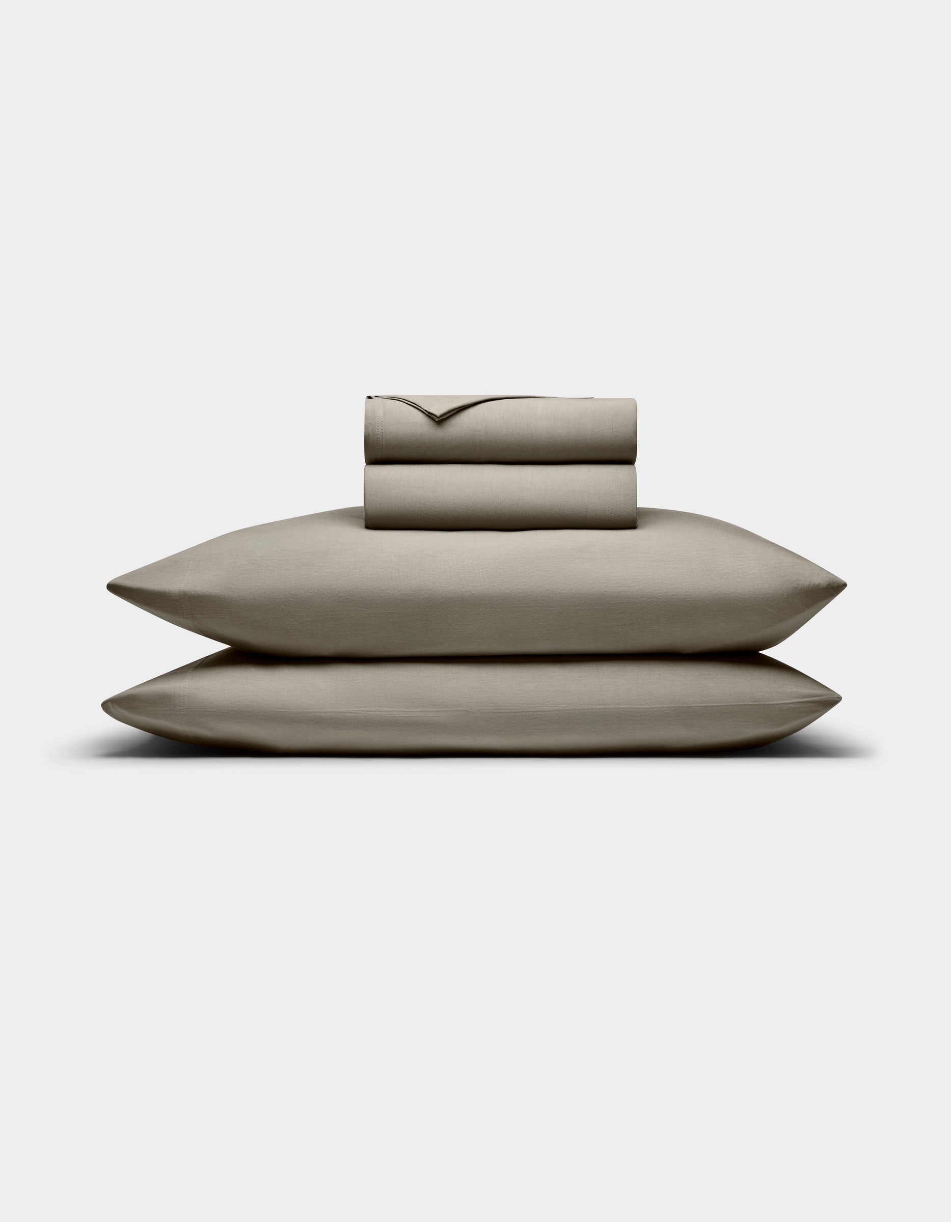 The Cozy Earth Bamboo Jersey Sheet Set, featuring a fitted sheet, flat sheet, and two stacked pillowcases in beige, is neatly folded and displayed against a plain white background.|Color:Stone