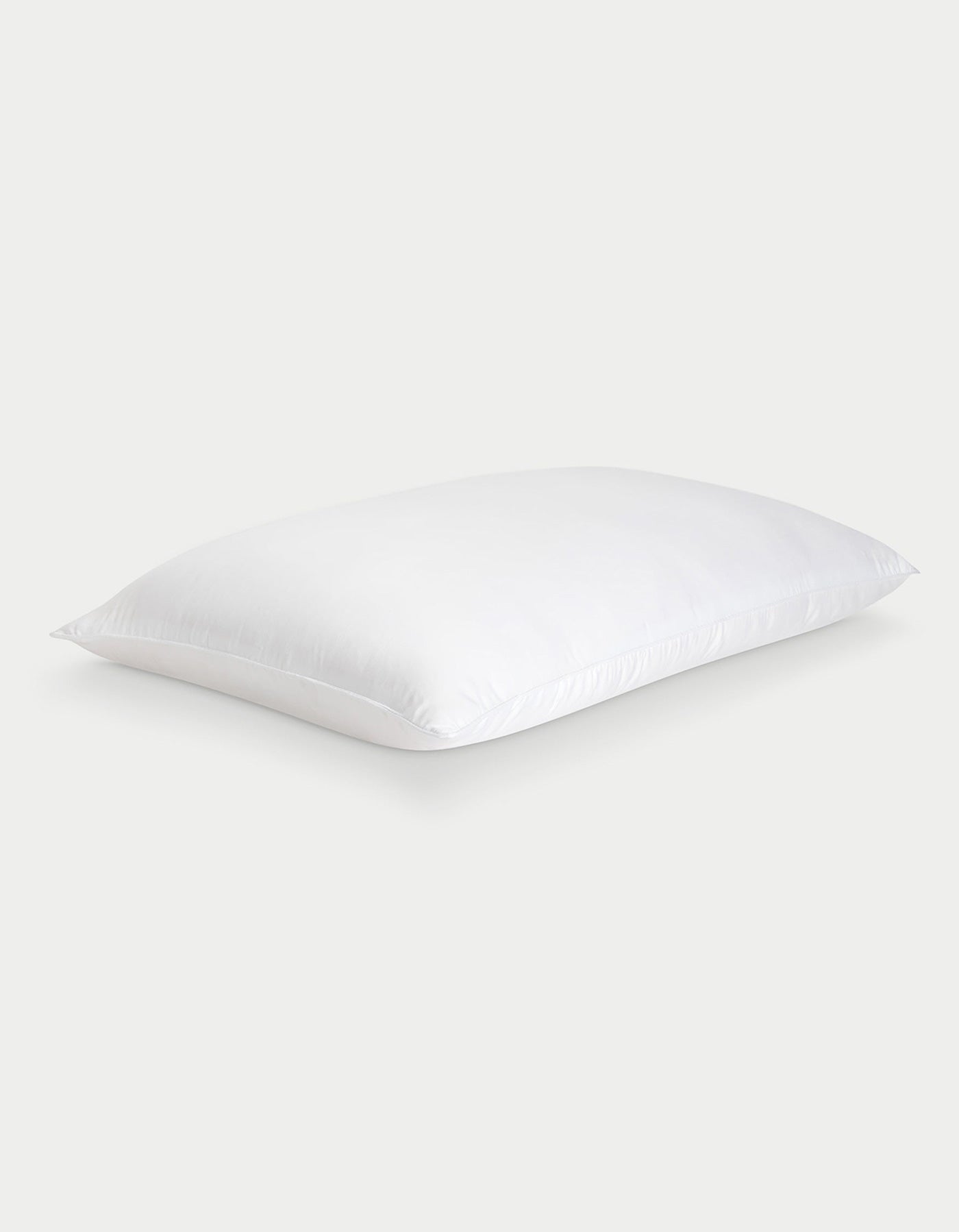 The Cozy Earth Silk Pillow, soft and rectangular with neatly finished edges, is shown against a light gray background. Its smooth white fabric highlights the luxurious feel of this premium pillow.
