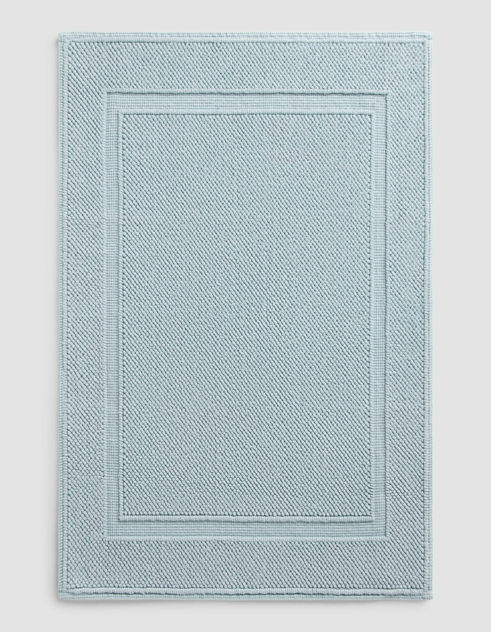 The Cozy Earth Classic Bath Mat features a rectangular shape in light blue with a textured surface and double border design, where two rectangles elegantly frame the center for a simple, refined look.|Color:Harbor Mist